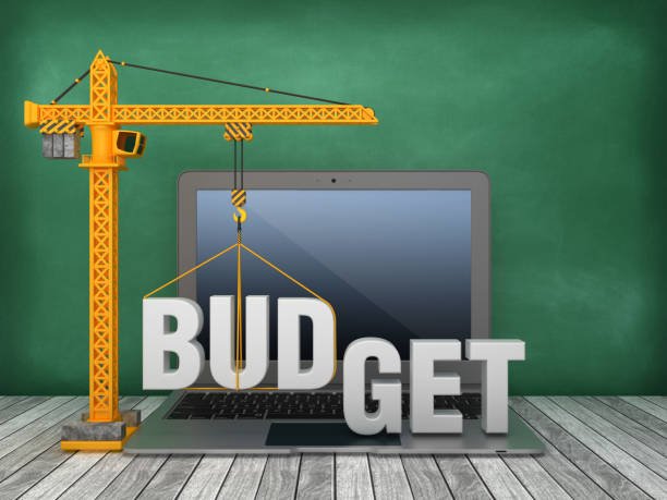 Tower Crane and Laptop with BUDGET Word on Chalkboard Background - 3D Rendering