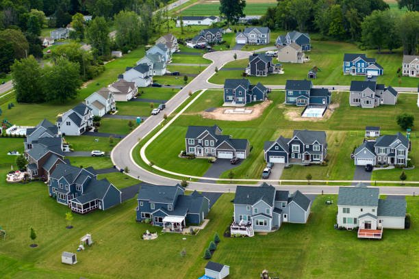 Low-density two story private homes in rural residential suburbs outside of Rochester, New York. Upscale suburban houses with large lot size and green grassy lawns in summer season.