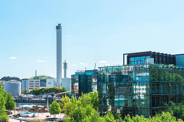 Modern buildings and the hammarby sjöstadsverk incineration plant tower rise above the green landscape of stockholm, sweden, on a sunny day