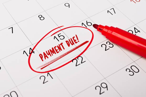 15th day of month marked with red circle. The phrase Payment Due, written in red text on a calendar page as a reminder. Closeup of a personal agenda, side view. Motivational advice