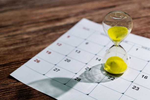 Calendar and hourglass on the table.