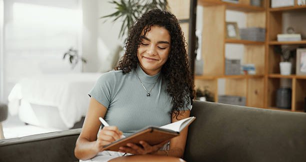 Writing, planning and smile with woman and notebook for inspiration, self care journal and reflection notes. Reminder checklist, mental health prompt and gratitude with person and diary at home