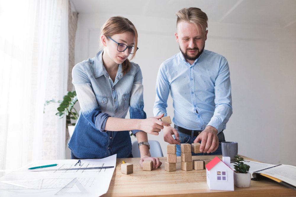 Man and woman stacking wooden block on working desk at office 