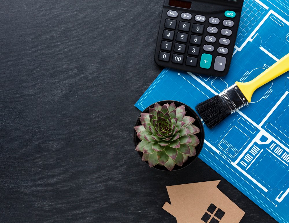 Blue print of a house with succulent plant and calculator 