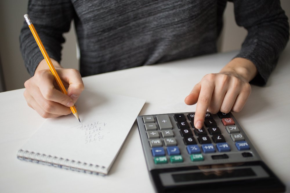 Closeup of accountant using calculator and writing 