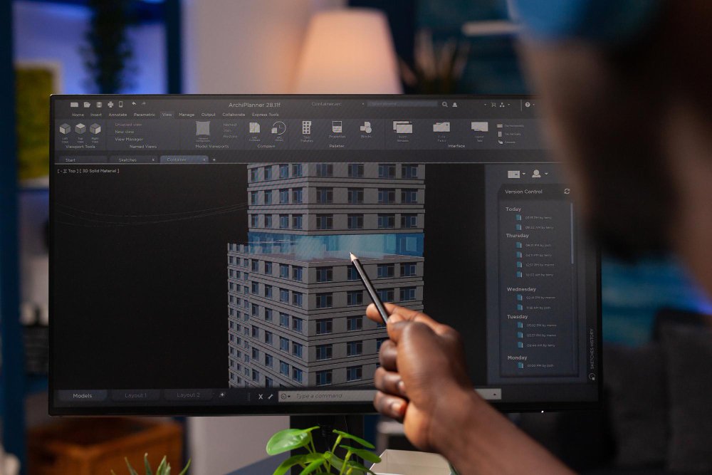 Architect engineer pointing at architectural building prototype analyzing construction model on computer. Businessman designer working remote from home at real estate project modeling sketch 